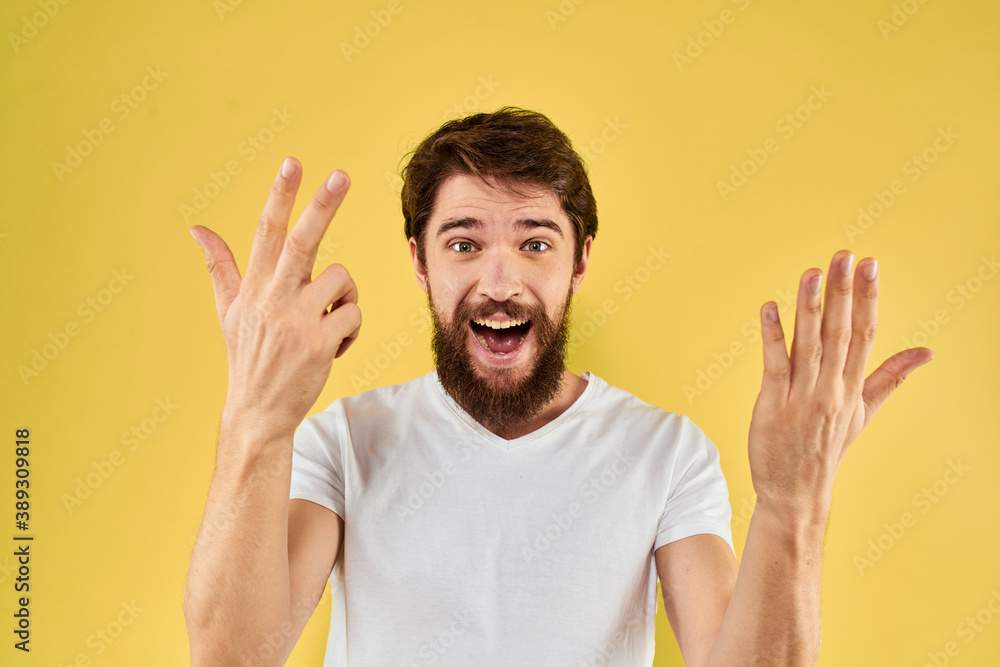 Bearded man emotions fun gesture with hands white t-shirt close-up yellow background Bearded man emotions fun gesture with hands white t-shirt close-up yellow background