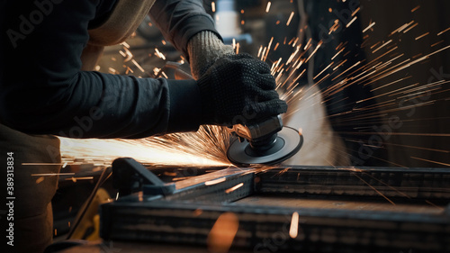 A man in gloves cuts metal with a circular saw, a lot of sparks. The working process