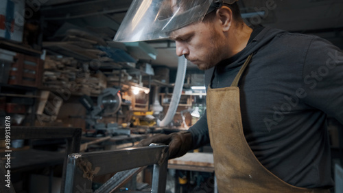 A blacksmith forges a metal piece with an unusual hammer