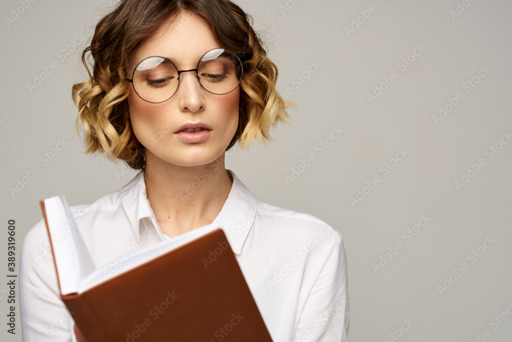 Business woman with notepad and glasses on a light background hairstyle success emotions Business woman with notepad and glasses on a light background hairstyle success emotions