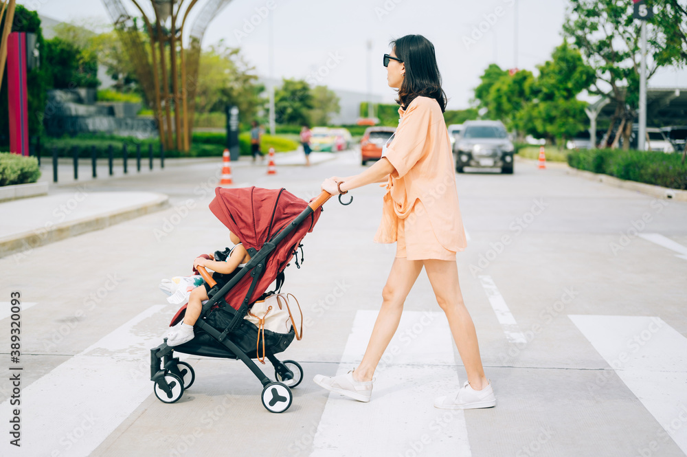 Mom and the little son on the stroller cross the road
