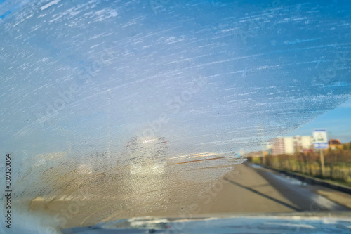 frost on the windshield of the car while driving on the highway. driving danger in poor visibility, front and background blurred with bokeh effect