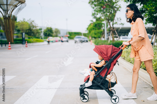 Mom and the little son on the stroller cross the road