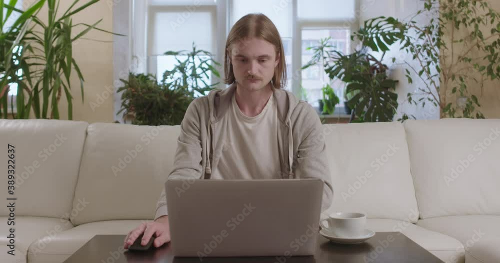 Young man is working on computer from home, focused moving computer mouse. Young man is working on computer from home, focused moving computer mouse.