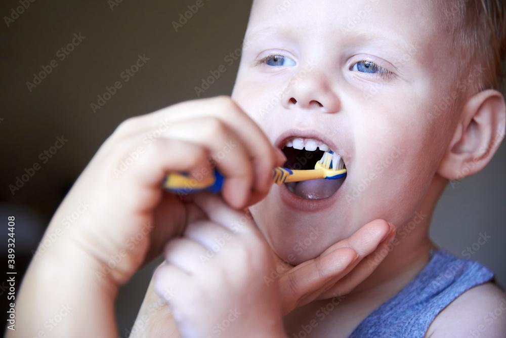 Mom teaches and helps her three-year-old son to brush his teeth. Mom teaches and helps her three-year-old son to brush his teeth.