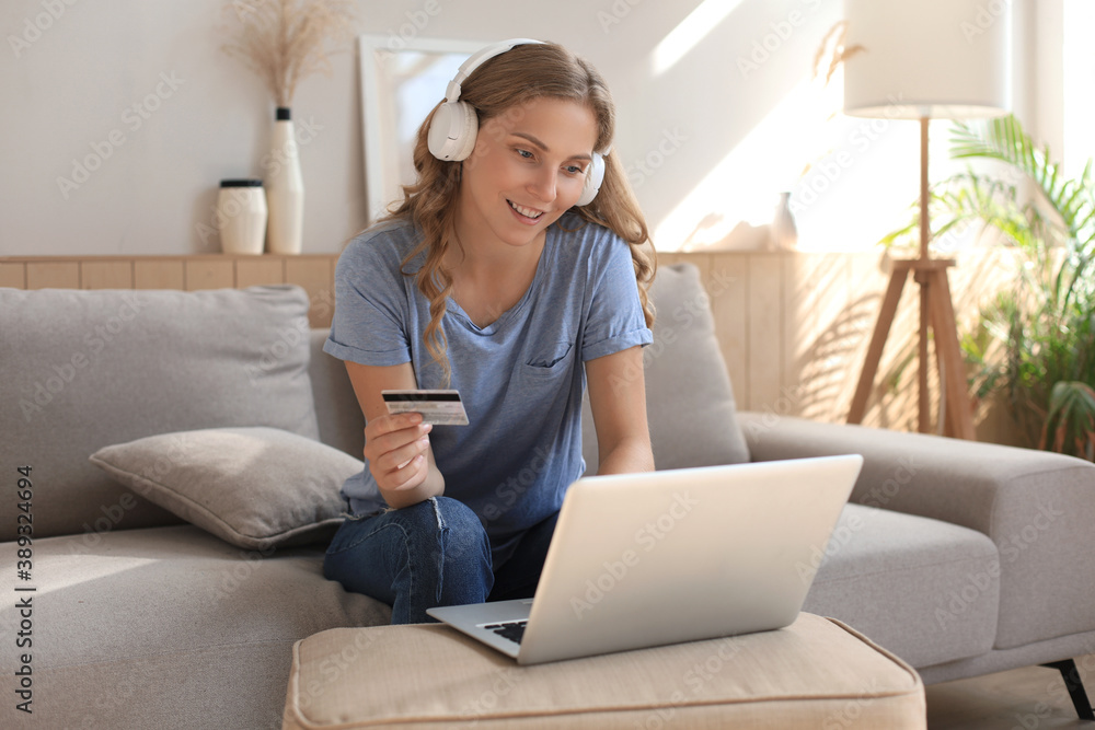 Happy natural blonde using credit card and laptop in the living room. Happy natural blonde using credit card and laptop in the living room.