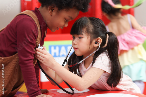 Fotografija Adorable kid pretending to be doctor, playing funny and holding doctor stethosco