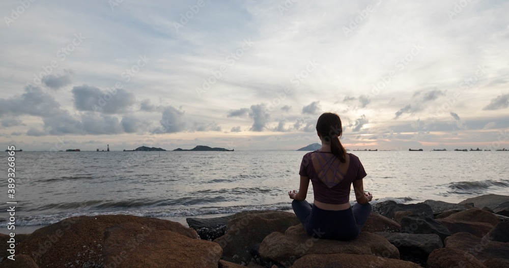 Naklejka premium Woman do yoga and sit beside the sea