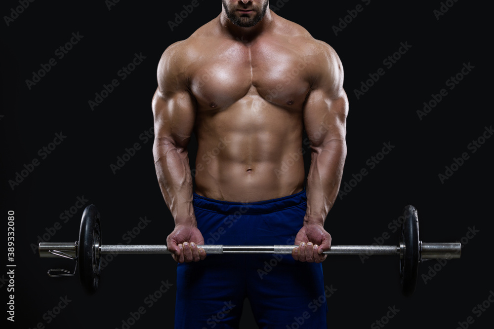 Handsome fitness man is standing with a heavy barbell ready to workout isolated on black background Handsome fitness man is standing with a heavy barbell ready to workout isolated on black background