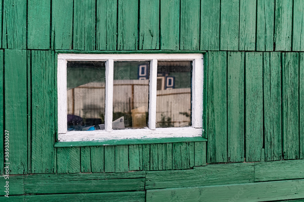 An old wooden small window with a frame of boards painted white and ...