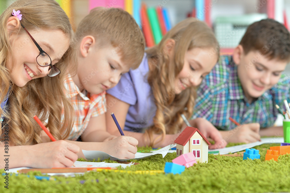 Fototapeta premium Children lying on floor drawing with pencils