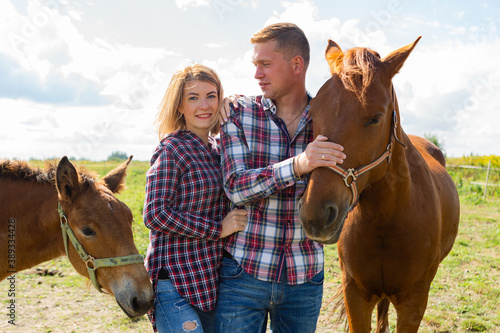 Young white couple have a vacation outdoor with a horses