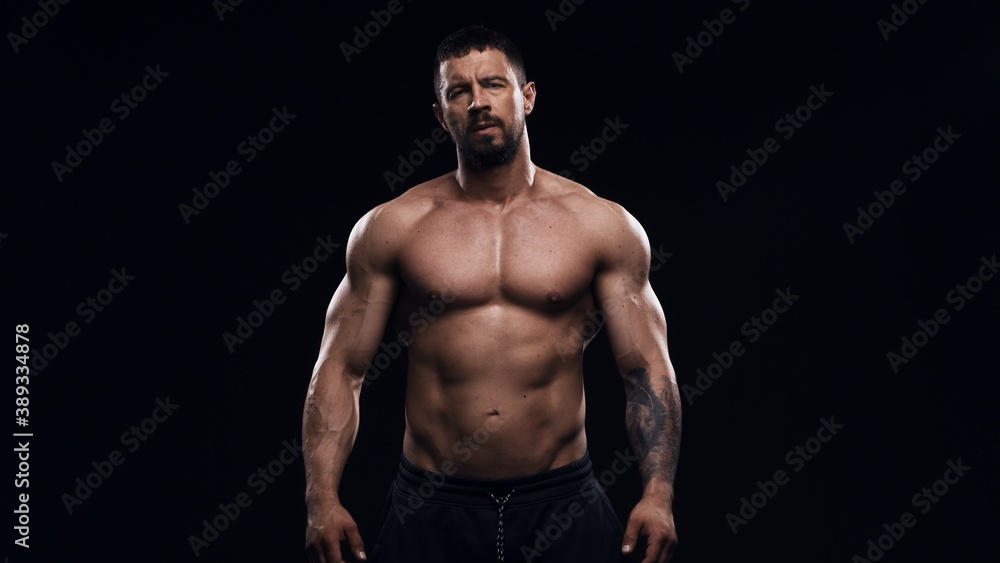 Fototapeta premium Fit and sporty bodybuilder over black background. Sportsman in studio. Sport and fitness concepts.