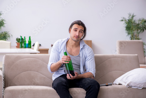 Young male alcoholic drinking wine at home