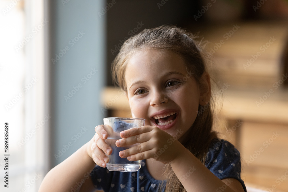 Overjoyed small 6s girl child drink clean clear water from glass feel thirsty dehydrated at home. Happy little kid enjoy still mineral aqua for body refreshment. Wellness, healthy lifestyle concept. Overjoyed small 6s girl child drink clean clear water from glass feel thirsty dehydrated at home. Happy little kid enjoy still mineral aqua for body refreshment. Wellness, healthy lifestyle concept.