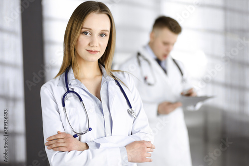 Professional beautiful woman-doctor with a stethoscope is standing with crossed arms in a clinic. Young doctors at work in a hospital. Medicine and healthcare concept