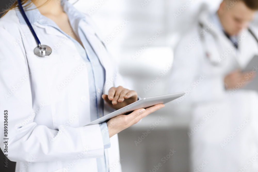 Unknown woman doctor is checking some data at computer tablet, close up. Young doctors at work in a hospital. Medicine and healthcare concept Unknown woman doctor is checking some data at computer tablet, close up. Young doctors at work in a hospital. Medicine and healthcare concept