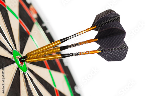Close up view on a fragment of the  professional sisal dartboard with three gilded darts in center (bullseye), isolate on a white background (mock up) © Mikhail
