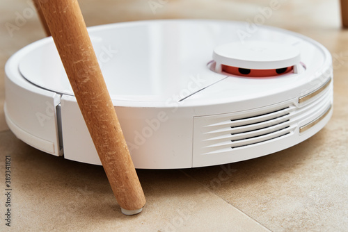 Robot vacuum cleaner working on floor with furniture, obstacles for robotic vacuum cleaner. Modern smart household