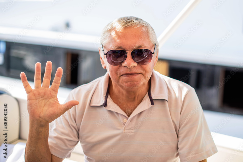 close-up portrait of happy senior man looking at camera on a background of yachts and a summer sea. close-up portrait of happy senior man looking at camera on a background of yachts and a summer sea.