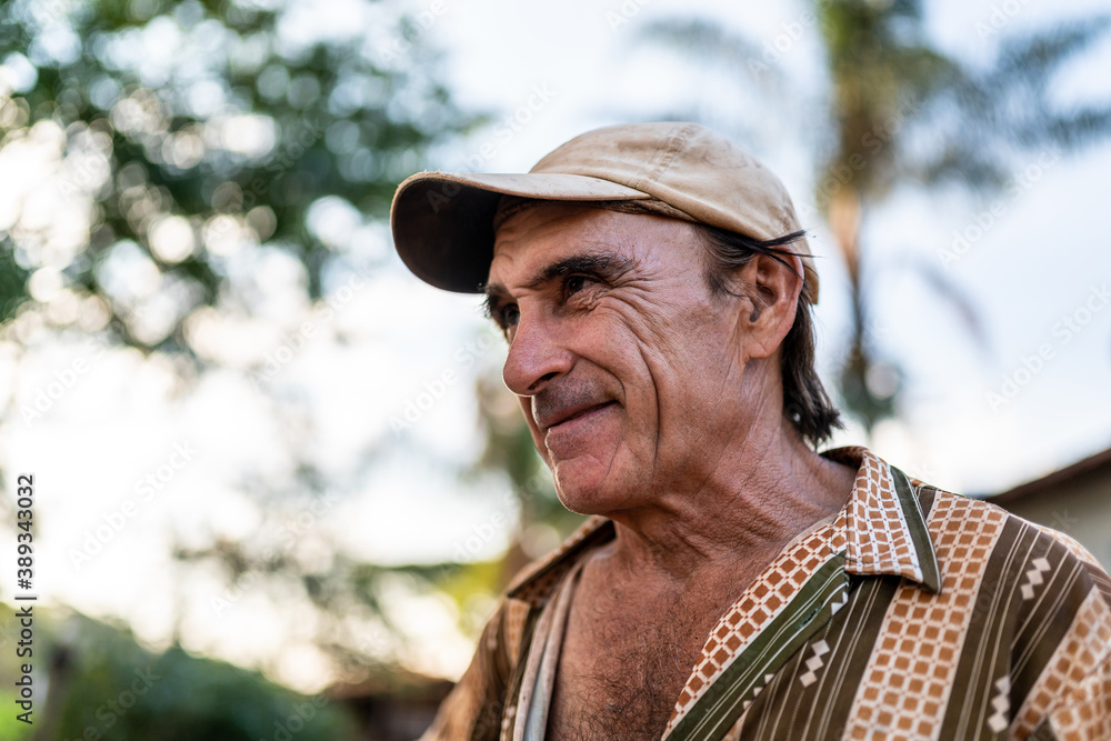 Portrait of smiling beautiful male farmer. Man at farm in summer day. Gardening activity. Brazilian elderly man. Latino people.