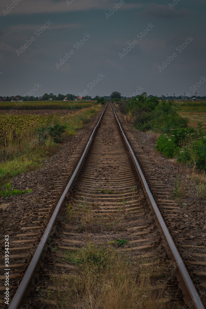 Worn and bent railorad tracks between the fields in Romania. Poor shape of railway tracks through the fields.