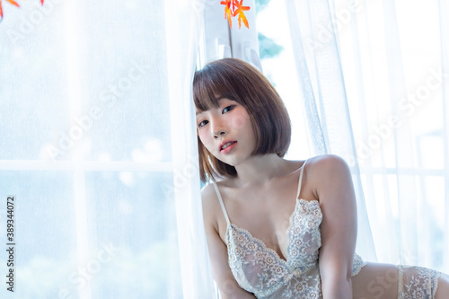 Portrait of young pretty sexy Asian woman wearing white bikini in her room.