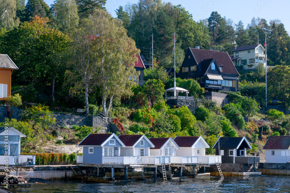 Many small houses on hillside with lots of trees. Seaside, fishing