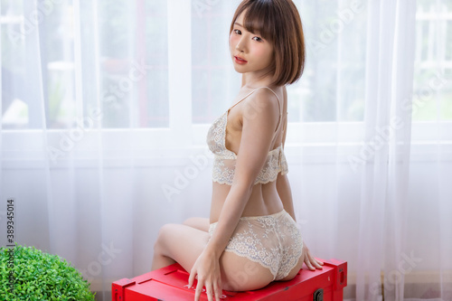 Portrait of young pretty sexy Asian woman wearing white bikini in her room.