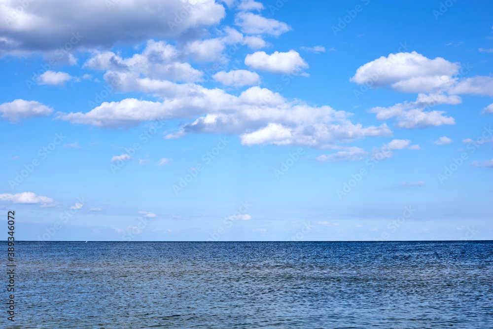 calm sea waters against a blue sky with clouds