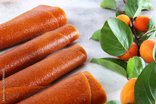 Apricot pastille is rolled up in the form of a tube on a white background. Natural and dietary product. Without preservatives. Low-calorie meals and snacks. photo