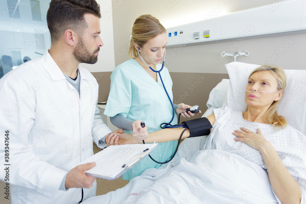 caring medical doctor taking mid age womans blood pressure caring medical doctor taking mid age womans blood pressure