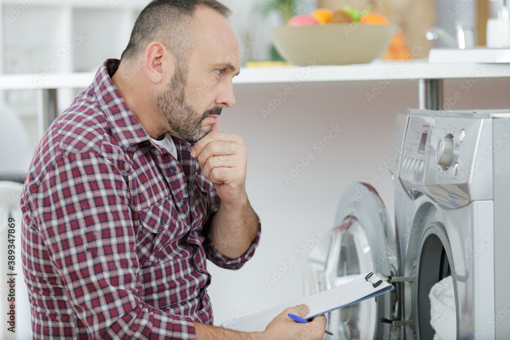 pensive plumber repairing washing machine