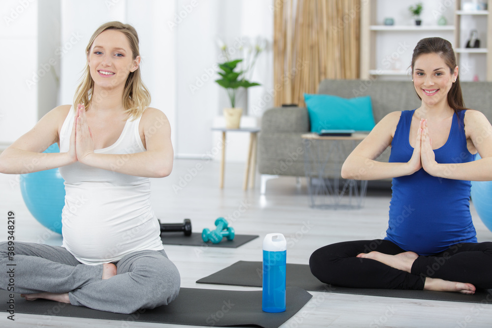 two pregnant female in gray sportswear relaxing after workout two pregnant female in gray sportswear relaxing after workout