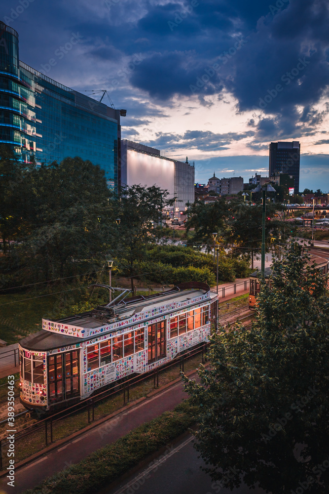 Obraz premium Old tram passing at sunset near Piazza Gae Aulenti in the new and modern district of Porta Nuova in Milan. Sky with clouds