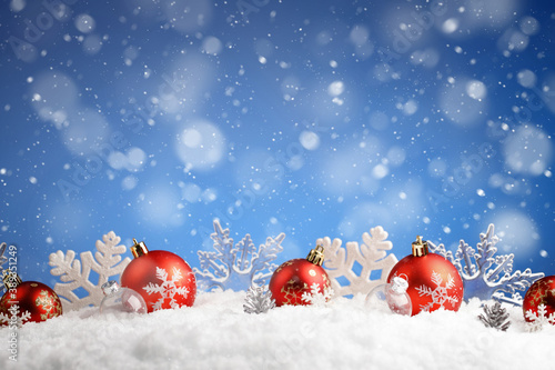 Row of Christmas balls and snowflakes laying on a snow