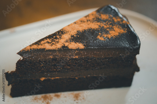 Close up triangle slice piece of delicious dark chocolate fudge cake