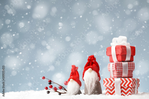 Christmas gnomes with gift boxes on the snow background