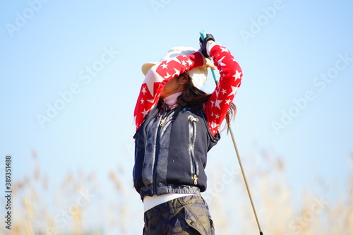 冬物のゴルフウェアーを着た30歳代の女性ゴルファーのアイアンショットのフォロースル―