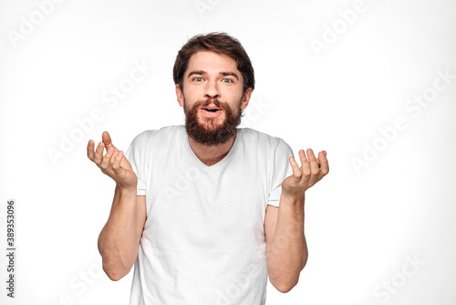 Bearded man in white t-shirt gesture with hands emotions light background