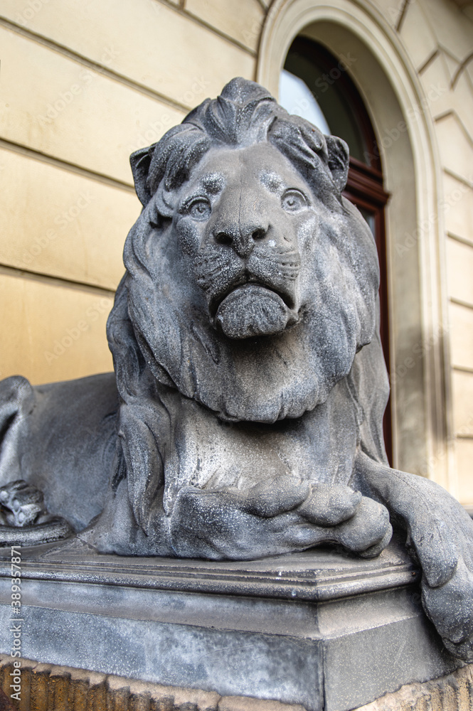 decorative bronze statue of a male lion in front of a building. 