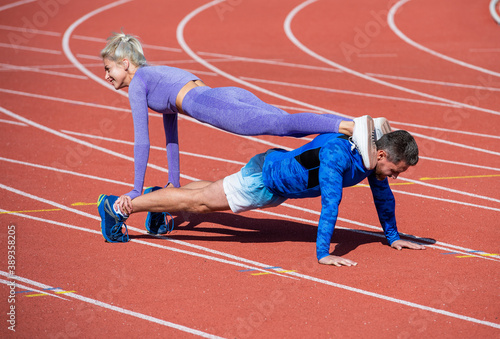 pumping up muscles. athletic man and woman in stand plank. male and female coach on stadium arena. healthy lifestyle. strength and power. sport couple training together. fitness partners pushing up