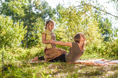 Woman masseuse demonstrates refreshing massaging methods in the forest. photo