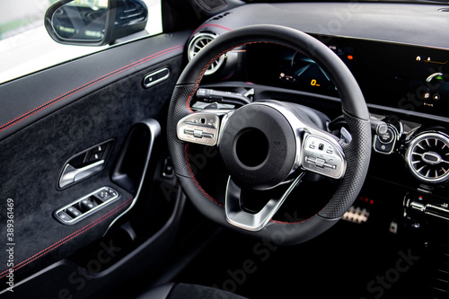 Close-up of the dashboard, speedometer, tachometer and steering wheel with phone setting and volume buttons. Luxurious car interior details. © Denis Sh