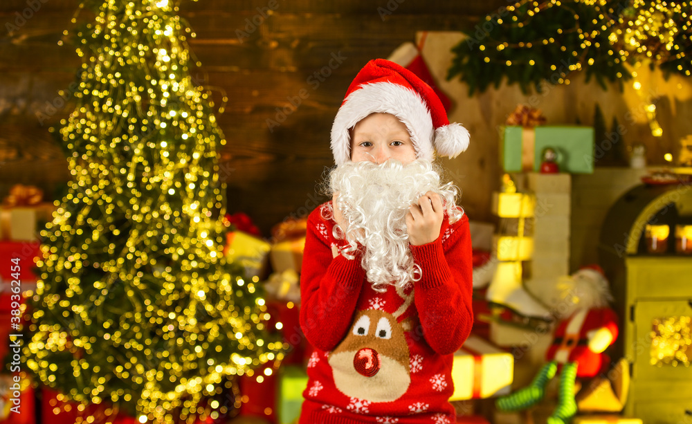 Best wishes. santa kid in hat and sweater. winter christmas holiday. buying gifts and presents. seasonal shopping. small boy ready for new year party. happy child celebrate xmas in decorated home