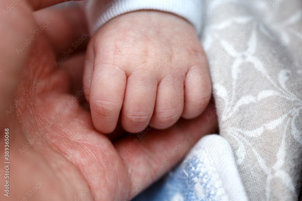 small fingers, hands of a newborn baby in a man's hand close-up . small depth of focus area