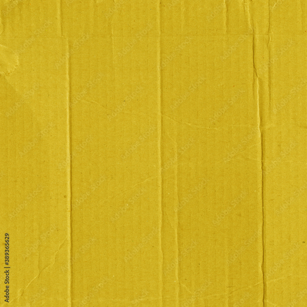 Fototapeta premium A yellow vintage rough sheet of carton. Recycled environmentally friendly cardboard paper texture. Simple and bright minimalist papercraft background.