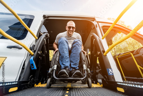 A man in a wheelchair on a lift of a vehicle for people with disabilities photo