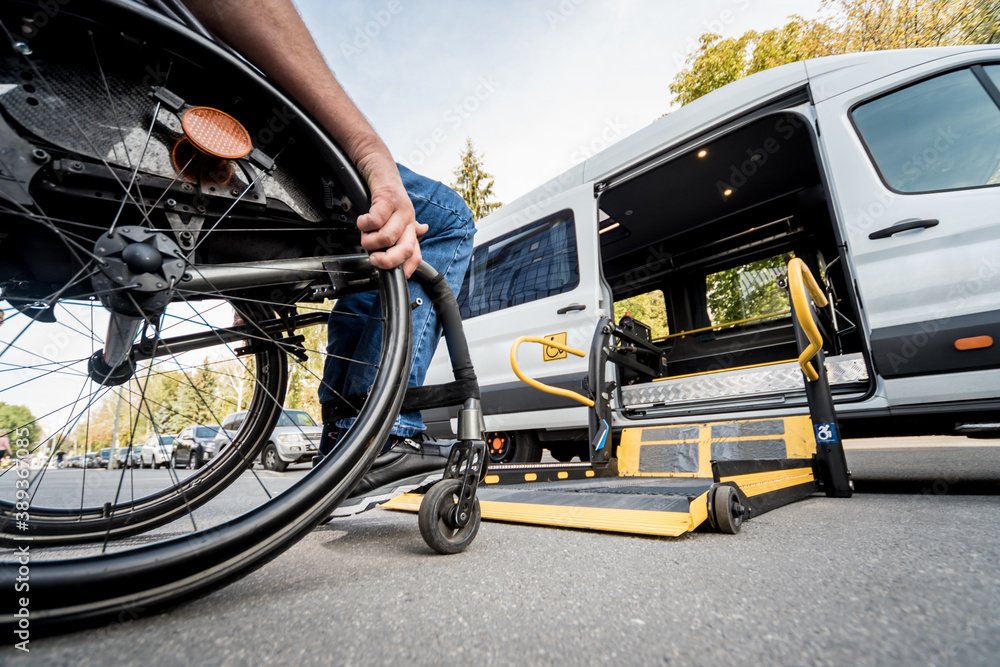 A man in a wheelchair moves to the lift of a specialized vehicle A man in a wheelchair moves to the lift of a specialized vehicle