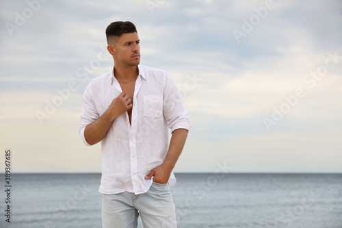 Handsome man on beach near sea. Space for text